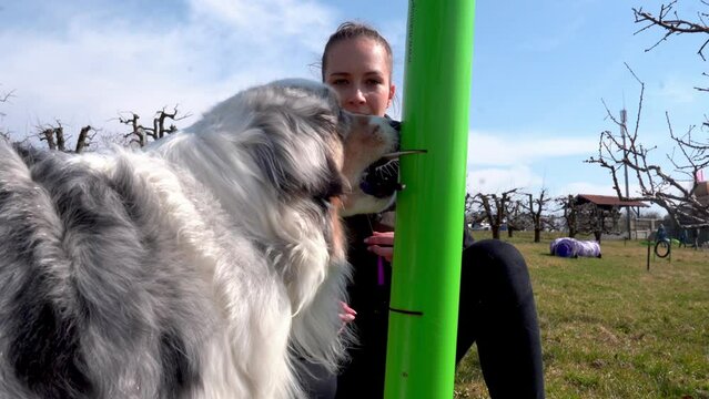 Caucasian white girl woman doing positive reinforcement trick training at dog area / dressing area with australian shepherd herding breed 