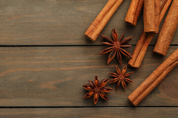 Cinnamon sticks and star anise on wooden table, flat lay. Space for text
