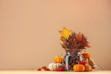 Composition with beautiful autumn leaves, berries and pumpkins on table against beige background, space for text