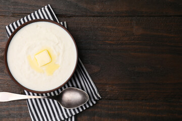 Delicious semolina pudding with butter in bowl and spoon on wooden table, top view. Space for text