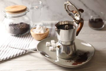 Brewed coffee in moka pot and spoon on white wooden table, space for text