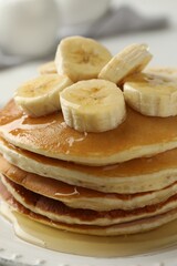 Delicious pancakes with bananas and honey on white table, closeup