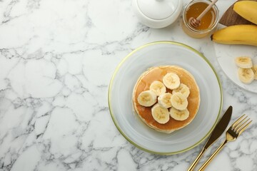 Delicious pancakes with bananas and honey served on white marble table, flat lay. Space for text