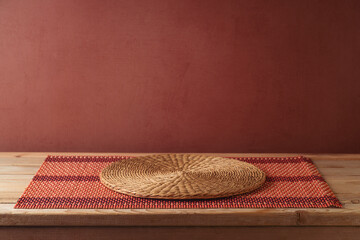 Empty wooden table with bamboo tablecloth and place mat over brown wall background.  Kitchen mock...