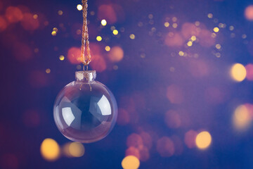 Christmas holiday background with transparent bauble ornament over festive bokeh lights
