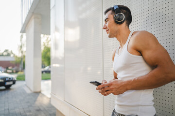 Portrait of young man outdoor use headphones and smart phone to play music or watch video podcast