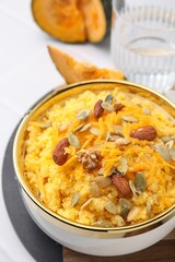 Tasty cornmeal with nuts, pumpkin and seeds in bowl on white table, above view
