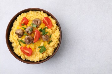 Tasty cornmeal with tomatoes, pepper and mushrooms in bowl on light table, top view. Space for text