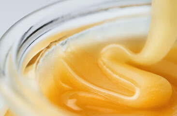 honey is poured into a glass jar, close-up