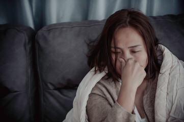 Asian sick woman sit on the sofa stay at home,The woman felt bad, wanted to lie down and rest,high fever