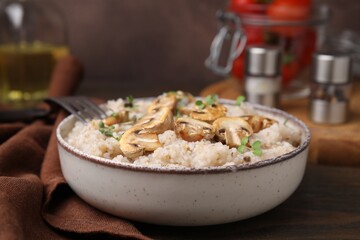 Delicious barley porridge with mushrooms and microgreens in bowl on table, closeup