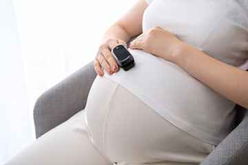 A pregnant woman measures the pulse with a heart rate monitor. Healthcare concept