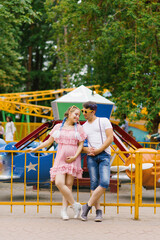 Young happy couple in love walks and has fun in an amusement park