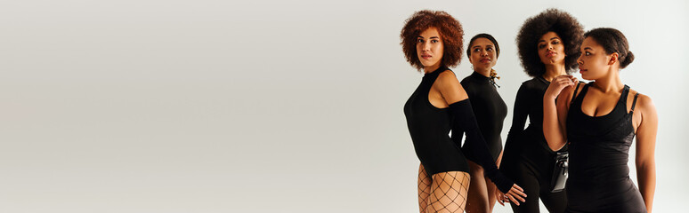 four appealing african american women in black alluring attire posing together, fashion, banner