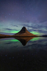 Polalichter in Island mit pyramiden Berg kirkjufell und Sternenhimmel, Wolken, und Spiegelung.
