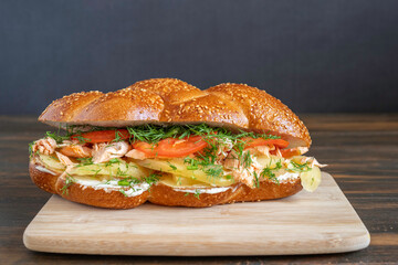 Challah Sandwich with grilled salmon, boiled potato, fresh tomatoes and fennel, cream cheese on wooden tray.