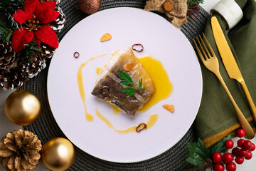 Bacalao al pil pil traditional tapa from north Spain. Codfish cooked with a delicious sauce made with oil, codfish and garlic. Christmas food served on a table decorated with Christmas motifs.
