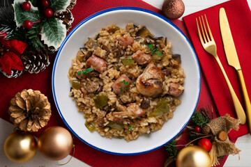 Rice paella with rabbit, sausages and green beans. Tapa traditional recipe in Valencia, Spain. Christmas food served on a table decorated with Christmas motifs.