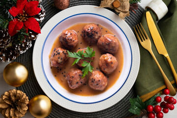 Meat meatballs with tomato sauce and vegetables. Christmas food on a table with decorations.