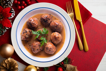 Meat meatballs with tomato sauce and vegetables. Christmas food on a table with decorations.