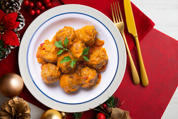 Meat meatballs with tomato sauce and vegetables. Christmas food on a table with decorations.