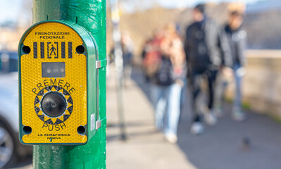 green traffic light activation button for pedestrian crossing at the crosswalk in Rome, Italy.