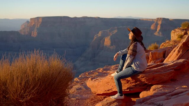 Young Native American woman wearing a cowboy hat standing at the amazing Grand Canyon - travel photography