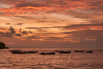 sunset over the sea with old boats, crystal bay in nusa penida