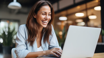 Woman working on a laptop and laughing in the office