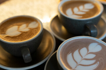 Three cups of coffee with latte art.