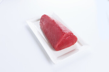 Fresh tuna on a white plate. A large piece of fresh tuna on a white platter. Healthy food. Natural omega. Copy the space bar. An isolated object.