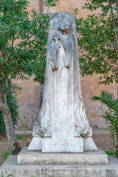 life-size stone statue of Giovanna Darco inside the garden of the basilica ss Bonifacio e Alessio in Rome.