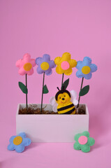 Fototapeta premium abelha no jardim de flores coloridas de feltro em fundo rosa 