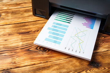 Modern laser printer with paper on wooden background