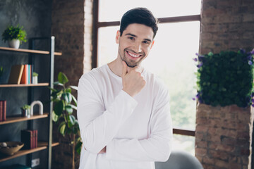 Photo of smart clever young guy wear white shirt arm chin thinking smiling indoors apartment room
