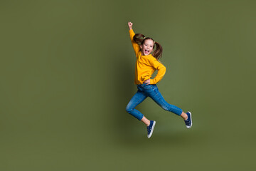Full length photo of overjoyed kid with ponytails hairdo dressed yellow shirt jumping raising fist...