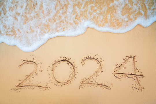 Happy New Year 2024 concept on the sea beach and wave on the sand shore