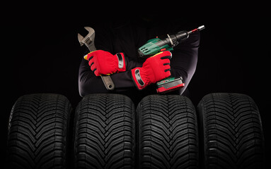 Winter car tires service and hands of mechanic with screwdriver and wrench tool on black background