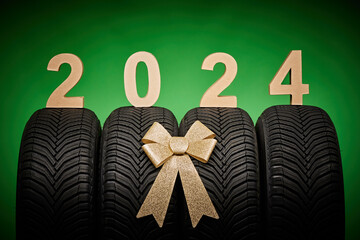 Car tires, new tyres, winter wheels isolated on green background with bow ribbon present 2024 new...