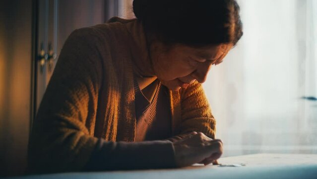 Lonely grandmother counting coins on table, poverty at senior age, low pension