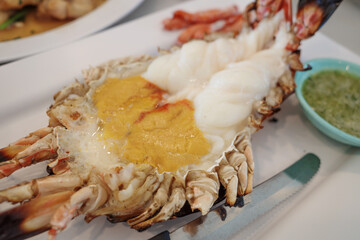 Cutting half grilled giant river prawn, famous local Thai luxury fine dining menu in Thailand, serve on white plate dish.