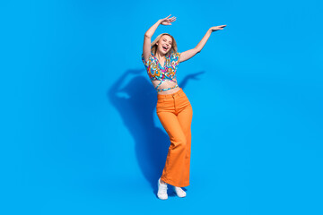 Full size photo of relaxed positive gorgeous girl wear stylish shirt hold hands up dancing isolated on vivid blue color background