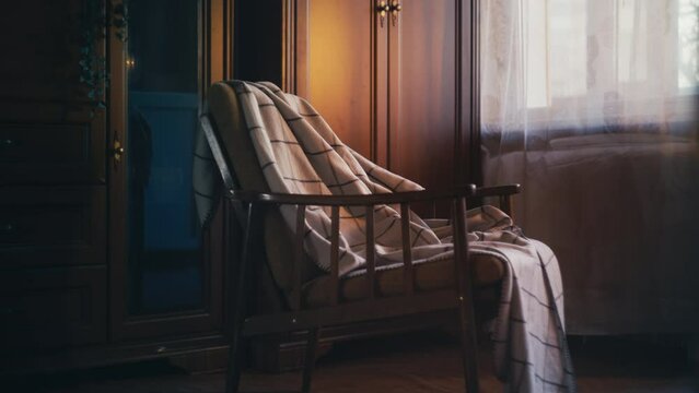 View on retro armchair with a blanket in a modest room, vintage style apartment