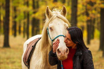 A pretty young woman and a white horse kiss for love