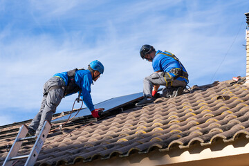 Two men on the roof of a house installing solar panels