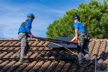 Two men installing solar panels on a house