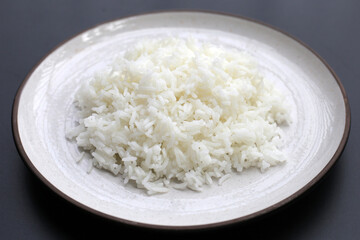 Cooked rice in plate on dark background.