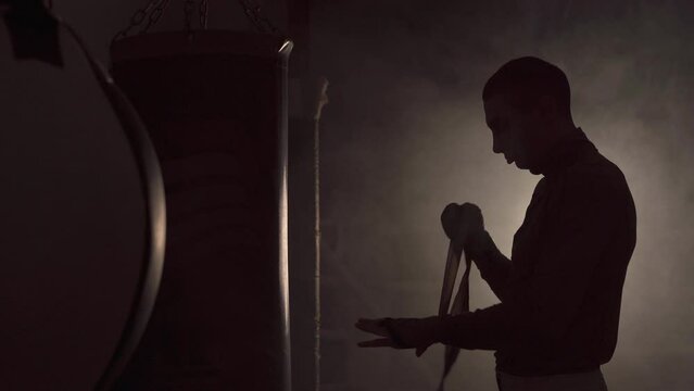 Young man boxer wrapping hands with boxing wraps. Strong hands and fists, ready for fight and active exercise.