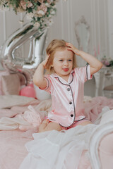 Fototapeta premium Blonde girl celebrates her 4th birthday in pink pajamas