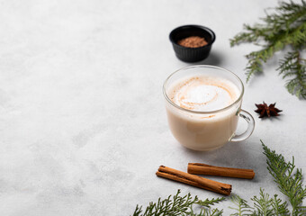 Spiced coffee latte or cappuccino with cinnamon sticks and anise star on a light background with...